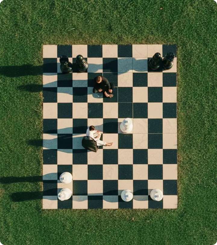Un tablero de ajedrez gigante sobre el césped, visto desde arriba, con personas de pie entre las piezas.